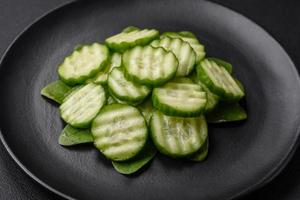 delicioso sano crudo Pepino rebanado en un negro cerámico plato foto