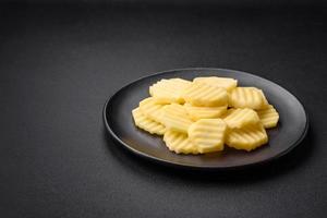 Raw fresh potatoes cut into slices on a black ceramic plate photo