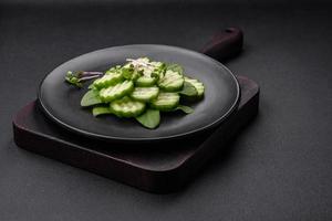Delicious healthy raw cucumber sliced  on a black ceramic plate photo