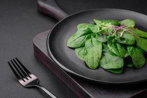 Fresh green spinach leaves on a black ceramic plate photo