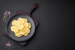 Raw fresh potatoes cut into slices on a black ceramic plate photo