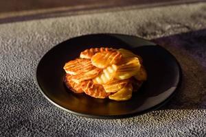 delicioso crujiente frito patatas en rebanadas en un negro cerámico plato foto