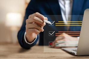 Businessman using laptop to do online checklist survey, doing assessment online survey answer test questions Digital form. photo