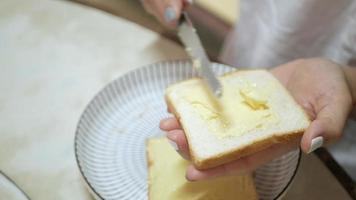 Nahaufnahmevideo Verteilen Sie frische Butter auf dem gerösteten geschnittenen Brot für eine gesunde Mahlzeit zum Frühstück. video