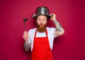 wondered chef with beard and red apron plays with pot photo