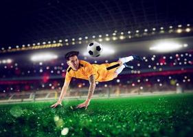 Football striker player with yellow team suit jumps at the soccer stadium photo