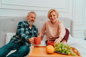 husband and wife have breakfast on the bed with coffee and fruit photo