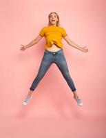 Girl jumps on pink background. Concept of freedom, energy and vitality photo