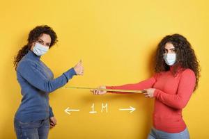 Friends keep distance between them of 1 meter. Concept of codiv-19 rules to avoid pandemic. yellow background. photo