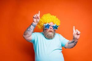 Fat man with beard, tattoos and sunglasses dances music on a disco photo