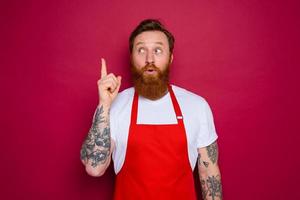 asombrado aislado cocinero con barba y rojo delantal foto
