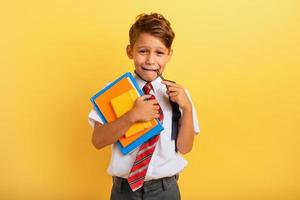 Child cries because he has a lot of school homework. Emotional expression. Yellow background photo