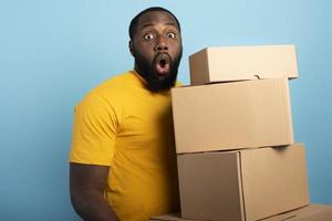 Surprised Man holds a lot of received packages. Cyan background photo