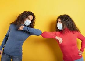 Friends greet each other while keeping their distance. Concept of codiv-19 rules to avoid pandemic. yellow background photo