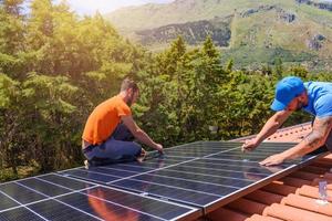 Workers assemble energy system with solar panel for electricity and hot water photo