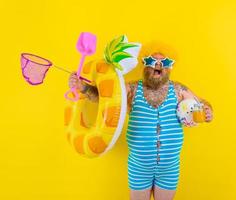 Fat amazed man with wig in head is ready to swim with a donut lifesaver photo