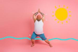 gracioso hombre con barba en yoga posición en estudio rosado antecedentes foto