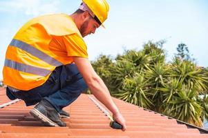 Technical worker takes measurements on the roof of a house photo