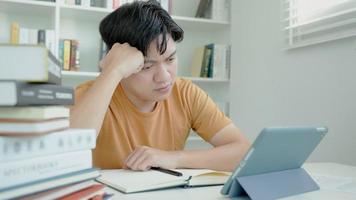 asiático estudiante hombre investigación muestra examen por tableta, masculino preparar para prueba y aprendizaje lecciones en el biblioteca. estrés, desesperación, prisa, malentendido lectura, desanimado, expectativa, conocimiento video