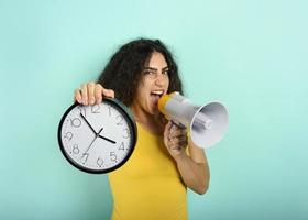 Woman screams with loudspeaker because is too late. angry expression. cyan background photo