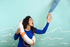 Woman is drowing and ask help with a message of a paper sheet. Cyan background photo
