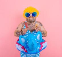 Fat man with beard and wig eats a popsicle and an icecream photo