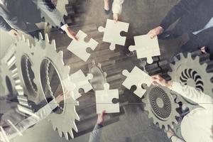 Teamwork of partners. Concept of integration and startup with puzzle pieces and gear overlay. double exposure photo