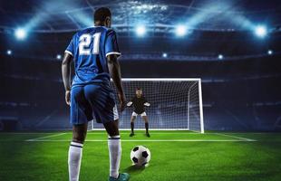 Soccer scene at night match with player in blue uniform kicking the penalty kick photo