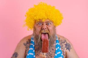 Fat hungry man with beard and wig eats a popsicle photo