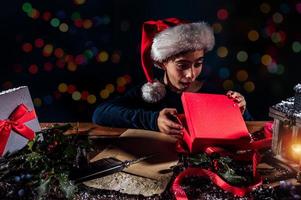 niño con Navidad sombrero escribe un letra a Papa Noel claus para regalos foto