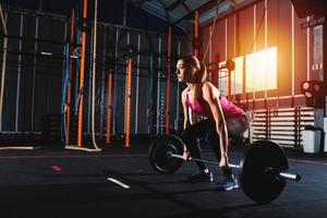 Athletic girl works out at the gym with a barbell photo