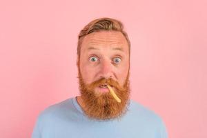 Afraid man with beard and tattoos eats fried potatoes photo