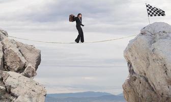 Business concept of businesswoman who overcome the problems reaching the flag on a rope photo