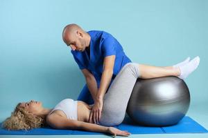 Girl performs exercises with a physiotherapist. Cyan background photo