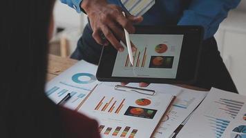 Financial analysts analyze business financial reports on a digital tablet planning investment project during a discussion at a meeting of corporate showing the results of their successful teamwork. video