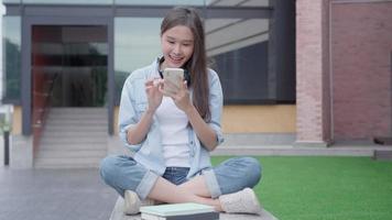 hermosa asiático mujer hembra estudiante charla equipo para trabajo proyecto. sonrisa niña contento estudiar en línea. libro en Universidad instalaciones. retrato hembra en internacional Asia universidad. educación, estudiar, colegio video