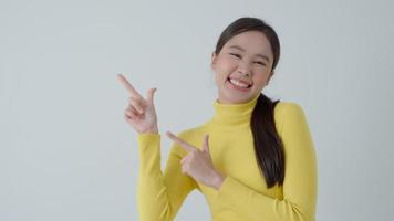 Portrait asian beautiful girl pointing blank space isolated background. Happy woman pointing on something. young female standing pointing finger sideways, billboard, introduction, advertisement, space video