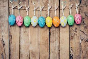 Colorful easter egg hanging on wood background photo