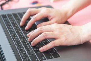 women typing on laptop in pink pastel colourful office with accessories photo