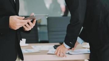 Financial analysts analyze business financial reports on a digital tablet planning investment project during a discussion at a meeting of corporate showing the results of their successful teamwork. video