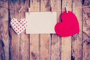 Two heart hanging and paper on clothesline and rope with wooden background photo