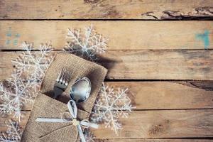 christmas table place setting and silverware, snowflakes on wooden background with space. photo