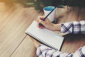 mano mujer escritura cuaderno en mesa en jardín con Clásico tonificado foto