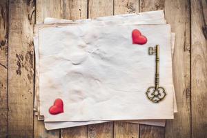 Old key and red heart on Old paper vintage on wood background with space photo