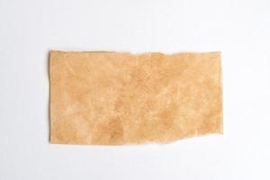 Close up of a ripped piece of brown paper on white background photo