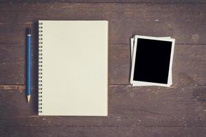 notebook and pencil with frame photo on wood table background with space