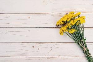 Yellow flowers of bouquet, top view on white wooden background texture with copy space photo