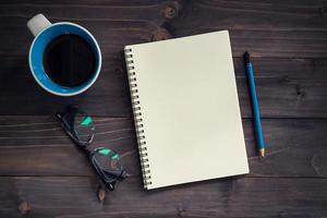 Office wood table with blank notepad, pencil, glasses and cup of coffee. photo