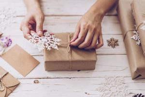 Woman hand making beautiful Christmas gift box at table photo