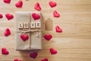 parte superior ver marrón regalo caja y rojo corazón en madera antecedentes para enamorado día con Copiar espacio. foto